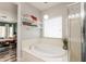 This is a bathroom with a soaking tub, glass shower, open shelves, and a view into the main bedroom at 11003 E Ravenna Cir, Mesa, AZ 85212