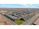 Wide aerial shot of a modern housing development, featuring well-spaced homes and a distant cityscape against a blue sky at 11444 E Utopia Ave, Mesa, AZ 85212