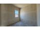 A simple, unfinished bedroom space featuring a single window, smooth concrete floors, and drywall-covered walls at 11444 E Utopia Ave, Mesa, AZ 85212