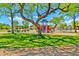 Community playground featuring a colorful play structure, shaded picnic pavilion, and grassy areas under a blue sky at 12709 N El Frio St, El Mirage, AZ 85335