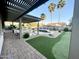 A well manicured backyard featuring a putting green, pool, fire pit, and covered seating area at 12753 W Vista Paseo Dr, Litchfield Park, AZ 85340