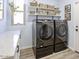 Bright laundry room featuring a modern black Samsung washer and dryer set, and shelves for storage at 12753 W Vista Paseo Dr, Litchfield Park, AZ 85340