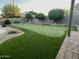 A large backyard putting green with artificial turf and decorative rocks and trees at 12753 W Vista Paseo Dr, Litchfield Park, AZ 85340