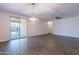 Open living room with wood-look tile flooring, modern light fixture, and sliding glass door to the patio at 13523 W Remuda Dr, Peoria, AZ 85383