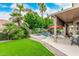Lush backyard featuring a covered patio, artificial turf, and serene pool with tiered fountains at 13566 N 93Rd Pl, Scottsdale, AZ 85260