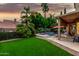 Lush backyard with green lawn, mature trees, a private pool, covered patio, and outdoor seating area at 13566 N 93Rd Pl, Scottsdale, AZ 85260
