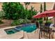 Backyard pool and spa surrounded by lush landscaping, an umbrella-covered seating area, and patio furniture at 13566 N 93Rd Pl, Scottsdale, AZ 85260