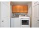 Bright laundry room with wooden cabinets above the side-by-side washer and dryer units at 13584 N 102Nd Pl, Scottsdale, AZ 85260