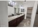 Bathroom with a double sink vanity, granite countertops, dark wood cabinets, and neutral tiling at 1492 S Pike Ln, Gilbert, AZ 85296