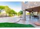 Expansive backyard featuring a stone patio, artificial grass, mature trees, and a covered patio space for outdoor dining and entertaining at 15237 S 19Th Way, Phoenix, AZ 85048
