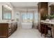 The bright bathroom includes a soaking tub, shuttered windows, and spacious and vanities at 15237 S 19Th Way, Phoenix, AZ 85048