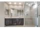 Spacious bathroom with double sinks, large mirror, and a frameless glass shower with seat at 16689 W Whispering Wind Dr, Surprise, AZ 85387