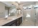 Bathroom featuring double sinks, a large mirror, and a frameless glass shower at 16689 W Whispering Wind Dr, Surprise, AZ 85387