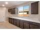Bright butler pantry features dark wood cabinets, light countertops and view to the exterior at 16689 W Whispering Wind Dr, Surprise, AZ 85387