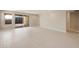 Open living room with ceramic tile flooring and sliding glass door to the exterior at 16689 W Whispering Wind Dr, Surprise, AZ 85387