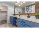 A bathroom with double sinks, painted blue cabinets and a large wooden mirror frame at 17235 W Statler St, Surprise, AZ 85388