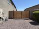 Backyard with gravel and a secure wooden gate between neighboring houses at 17427 W Hadley St, Goodyear, AZ 85338