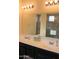 Bathroom with double sinks, dark cabinets, white counters, decorative lighting, and large mirror at 17427 W Hadley St, Goodyear, AZ 85338
