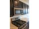 Up-close view of the stainless steel microwave and cooktop, granite countertops, and dark cabinets at 17427 W Hadley St, Goodyear, AZ 85338