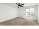 Bedroom boasts natural light from a large window, a ceiling fan, and neutral carpet at 18663 W Vogel Ave, Goodyear, AZ 85338