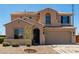 Two-story home with a beige exterior, arched entry, landscaping, and a two car garage at 18663 W Vogel Ave, Goodyear, AZ 85338