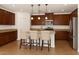 Eat-in kitchen with an island, granite countertops, stainless steel appliances and brown cabinets at 18663 W Vogel Ave, Goodyear, AZ 85338
