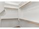 Spacious walk-in closet features white shelving with wooden supports and carpeted flooring at 18663 W Vogel Ave, Goodyear, AZ 85338