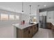 Spacious kitchen featuring a large island with a sink, stainless steel appliances, and modern pendant lighting at 19321 W Luke Ave, Litchfield Park, AZ 85340