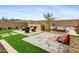 Landscaped backyard featuring a stone patio, built-in seating, and a modern outdoor fireplace at 19426 W San Juan Ave, Litchfield Park, AZ 85340