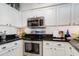 Close-up of kitchen with stainless steel oven and microwave, set in white cabinetry and black countertops at 20100 N 78Th Pl # 1048, Scottsdale, AZ 85255