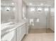Bright bathroom featuring dual vanities and a frameless glass shower with a tiled bench and modern fixtures at 24791 N 169Th Dr, Surprise, AZ 85387