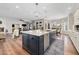 This kitchen features an island with a sink, stainless steel appliances, white cabinets, and hardwood floors at 3665 S Jojoba Way, Chandler, AZ 85248