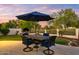 Outdoor patio with wrought iron table and chairs under an umbrella, overlooking lush landscaping and golf course at 3665 S Jojoba Way, Chandler, AZ 85248
