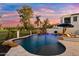 A serene backyard featuring a custom pool with a rock waterfall, integrated lighting, and a cozy fire pit area at 3665 S Jojoba Way, Chandler, AZ 85248