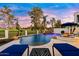 A private backyard oasis with a pool, rock waterfall feature, fire pit and golf course views at twilight at 3665 S Jojoba Way, Chandler, AZ 85248