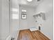 Bright, compact laundry room with wood floors, shelves and a window at 5881 N 193Rd Dr, Litchfield Park, AZ 85340