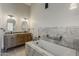 Bathroom with double sinks, granite countertops, wood cabinets, and bathtub with stone tile surround at 625 E Silver Creek Rd, Gilbert, AZ 85296