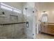 Beautiful bathroom featuring stone tile in shower, glass door, wood cabinets, granite countertops, and a modern mirror at 625 E Silver Creek Rd, Gilbert, AZ 85296