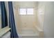 Bright bathroom with a white bathtub, window, and shower with a blue curtain at 6388 W Donald Dr, Glendale, AZ 85310