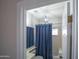 Cozy bathroom featuring a toilet, bathtub with a blue curtain, and window for natural lighting at 6388 W Donald Dr, Glendale, AZ 85310