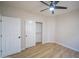 Neutral bedroom with wood-look flooring, fan, closet, and two white doors at 6388 W Donald Dr, Glendale, AZ 85310