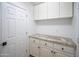 Bright laundry room with white cabinets, speckled granite counters, and a convenient storage space at 6388 W Donald Dr, Glendale, AZ 85310