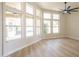 Living room featuring bright sunlight, fan, wood look flooring, and expansive windows providing view of backyard pool at 6388 W Donald Dr, Glendale, AZ 85310