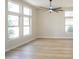 Neutral living room featuring wood look flooring, multiple bright windows, and a modern ceiling fan at 6388 W Donald Dr, Glendale, AZ 85310