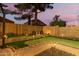 Lush backyard putting green featuring synthetic turf, landscape lighting, and a beautiful dusk sky at 712 W Jade Dr, Chandler, AZ 85248