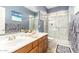Well-lit bathroom featuring dual sinks, framed mirrors, and a modern glass enclosed shower with marbled walls at 712 W Jade Dr, Chandler, AZ 85248