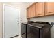 Functional laundry room area featuring modern washing and drying machines, with upper cabinets for storage at 712 W Jade Dr, Chandler, AZ 85248