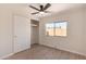 This bedroom features a ceiling fan, wood-look floors, a large window, and a closet at 7442 E Baseline Rd, Mesa, AZ 85209