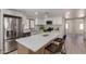 Well-lit kitchen with stainless steel appliances, quartz countertops, a kitchen island with barstool seating and white cabinets at 7442 E Baseline Rd, Mesa, AZ 85209