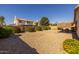 Backyard with gravel, a covered patio, block wall, and some mature trees beyond the wall at 8952 W Monte Vista Rd, Phoenix, AZ 85037